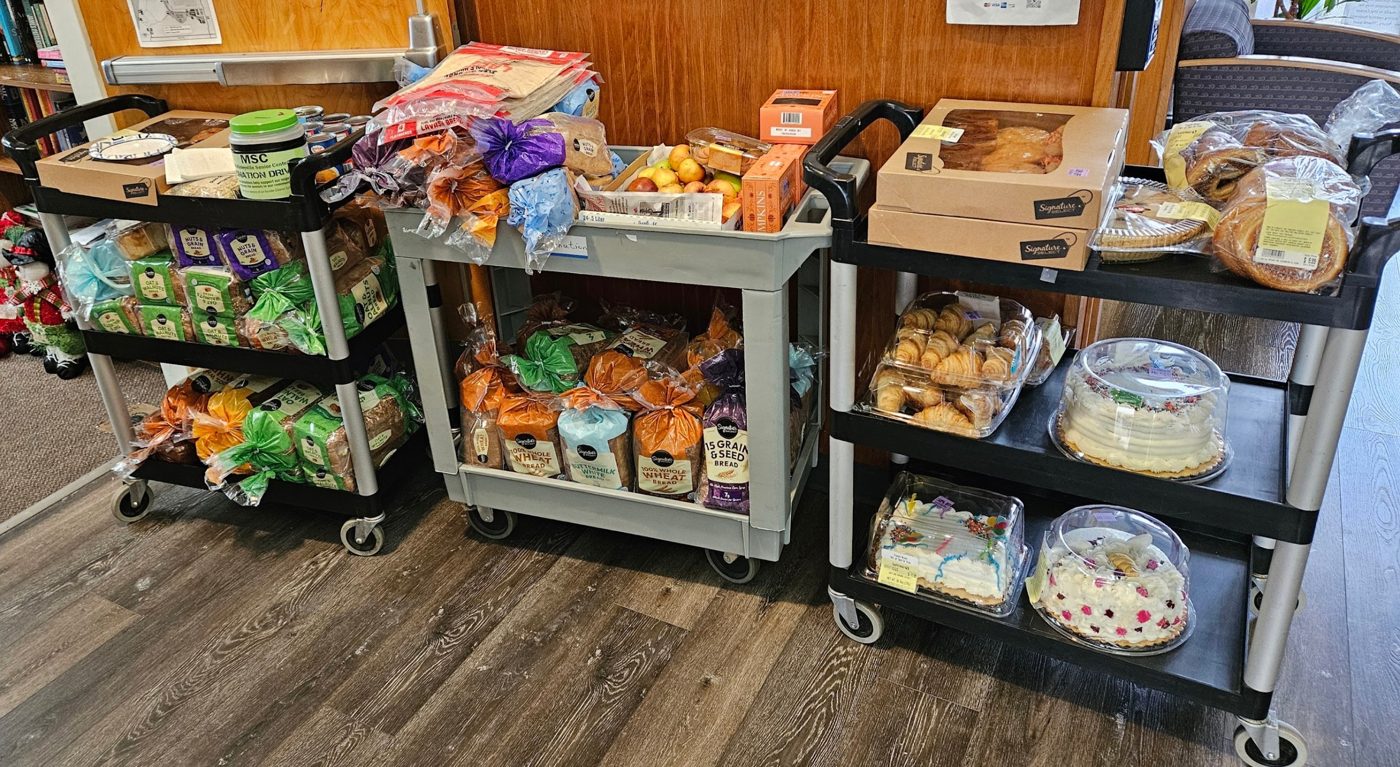 Three carts loaded with bread, pastries, pies, and cakes from the Safeway bakery