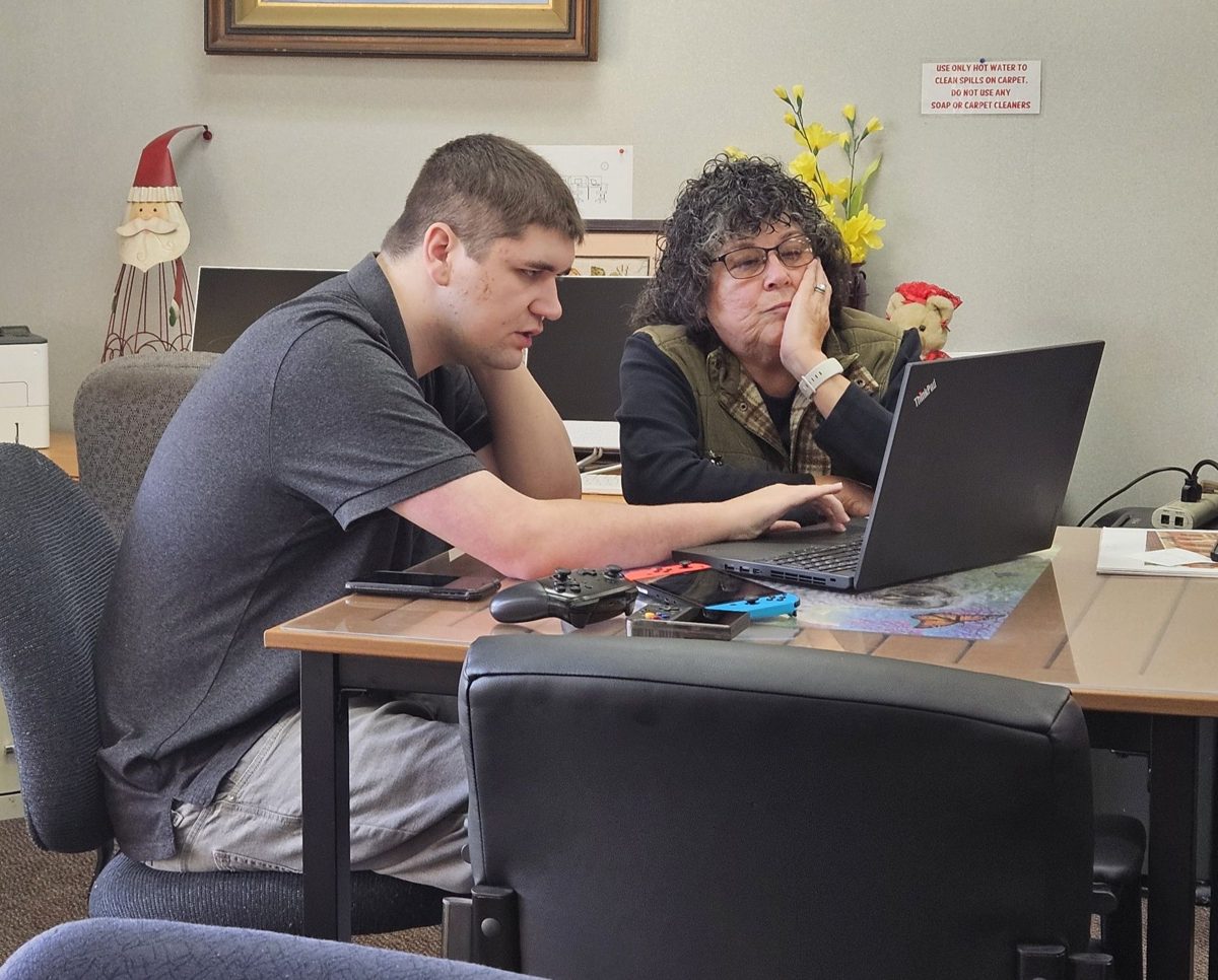 Instructor Trevin Maciel helping a member on a laptop
